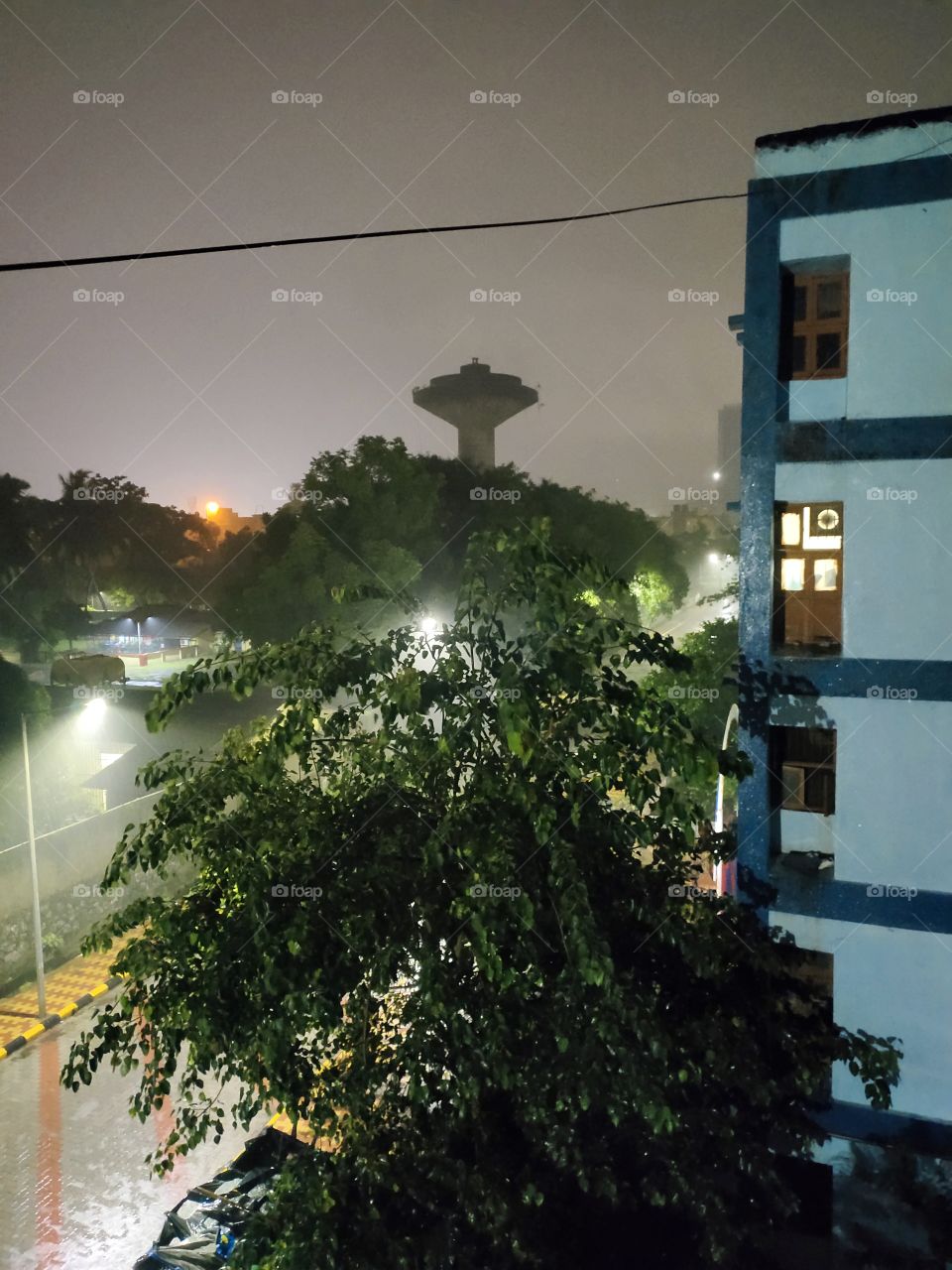 Pleasent Weather During Heavy Rain
Night Scene Towards City

it's Combination of Nature
e.g.
Super illumination,
Rain Drops,Green Tree ,Flats corner and Water tank...