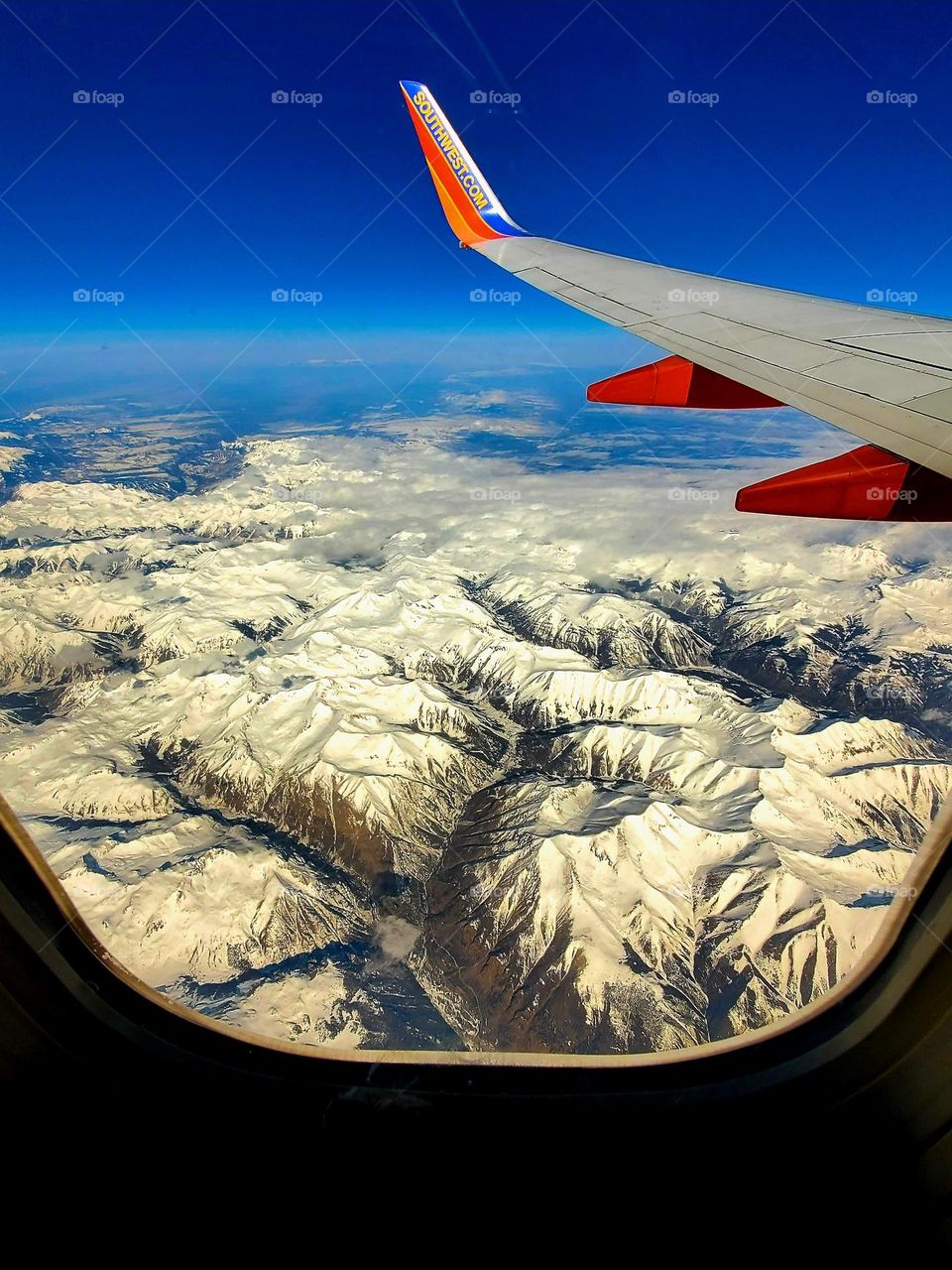 A clear winter day flying over snow covered Rocky Mountains in Colorado on a Southwest Airlines Boeing 737