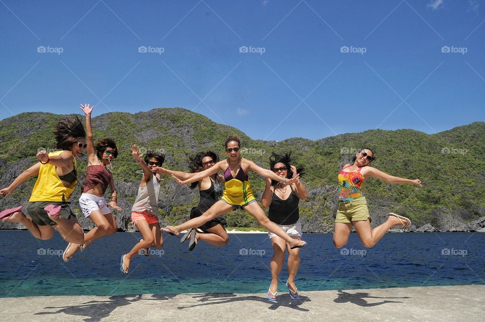 Group of female friends jumping on lakeshore