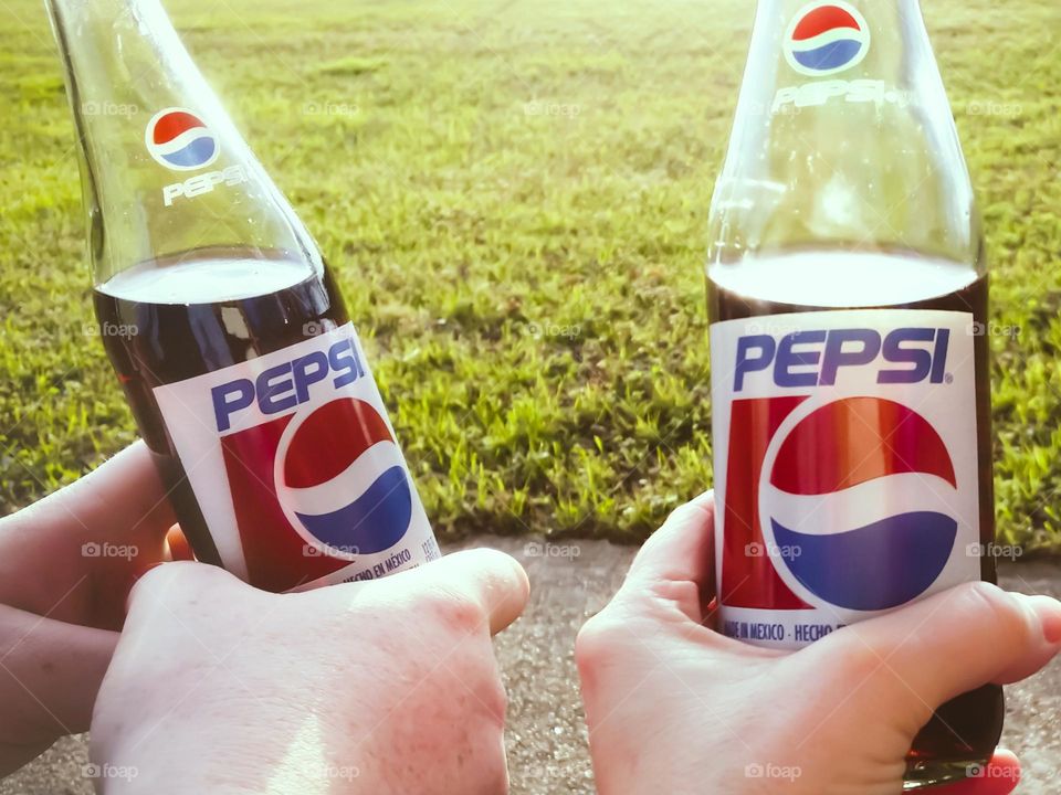 Two people holding Pepsi sitting Outside