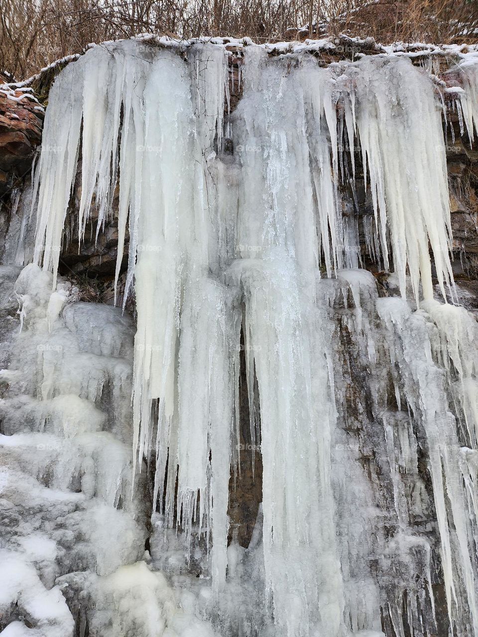 Sharp dangling icicles look intimidating as they hang off a rock wall signaling there once was active water runoff