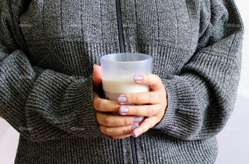 Woman wearing gray tracksuit holding a glass of milk