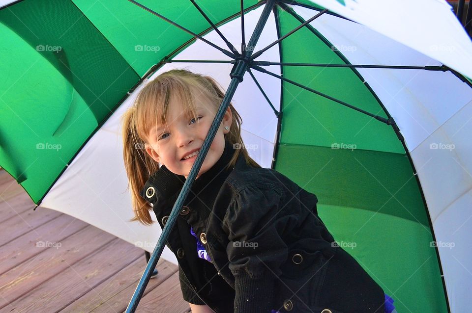 Little girl under the umbrella. Little girl having fun under an umbrella