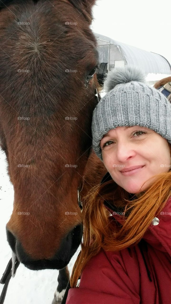 A selfie of a women with a fawn horse during winter