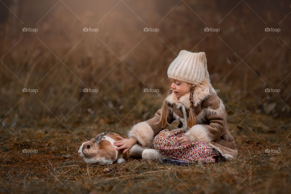 Cute Little girl with bunny in a forest at misty autumn evening 