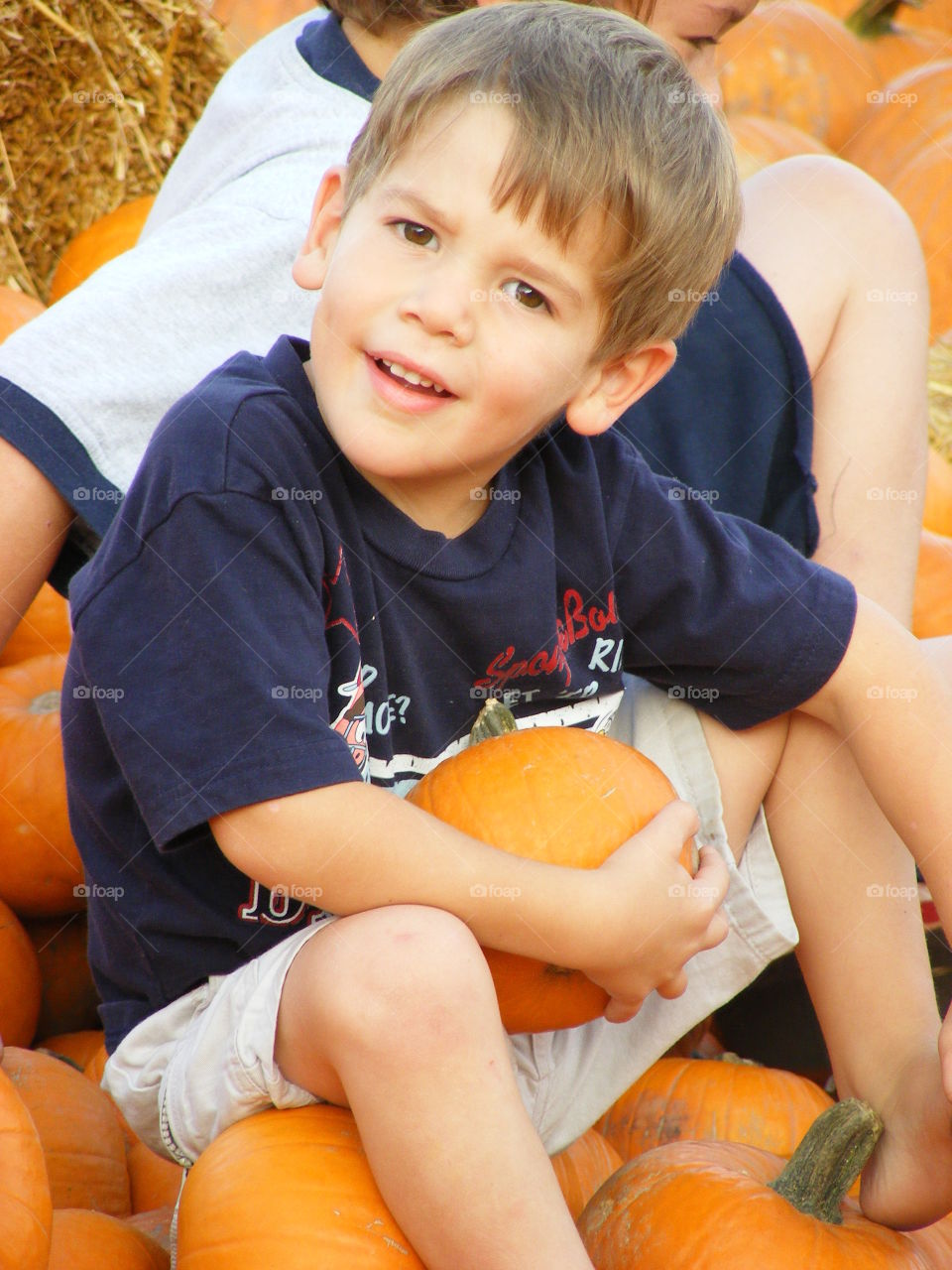Boy holding a pumpkin with a strange look on his face.