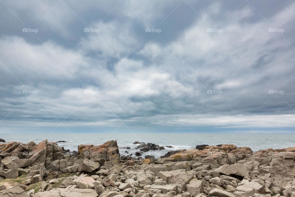 Cloudy sky over the ocean and rocky coastline 