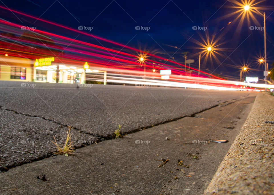 A long exposure night photo of South Congress Avenue as cars pass by, leaving a trail of lights. 