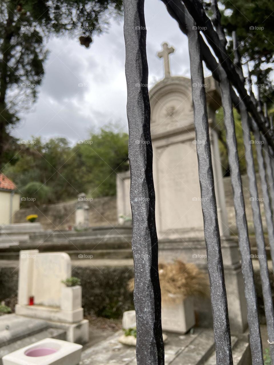 Looking through a metal fence into a cemetery.