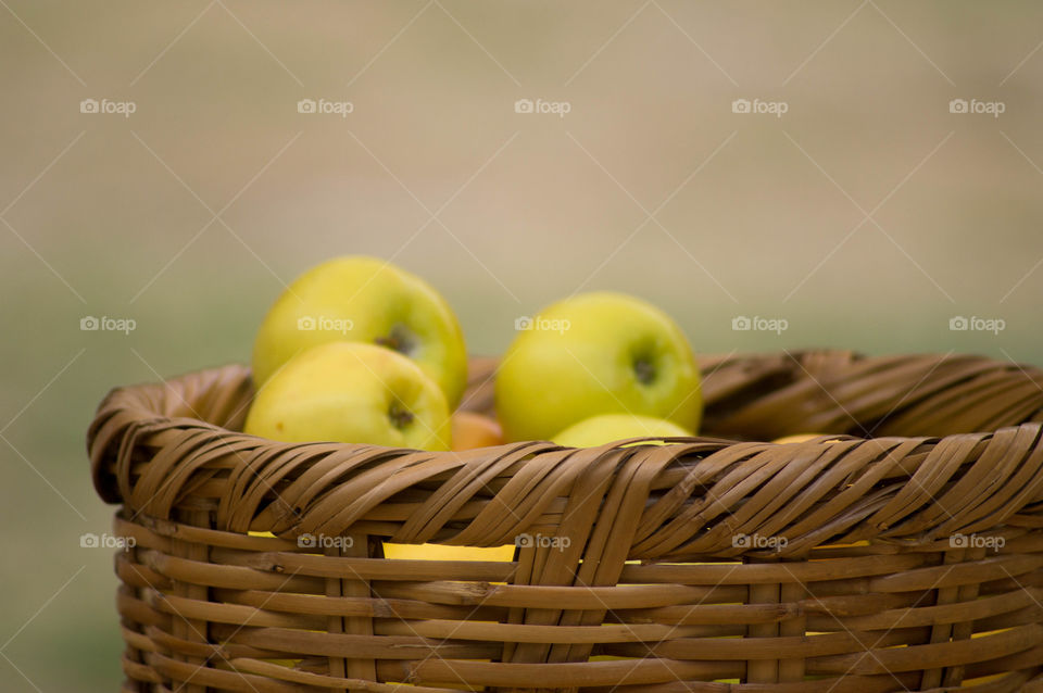 yellow Apples in a basket with brown background