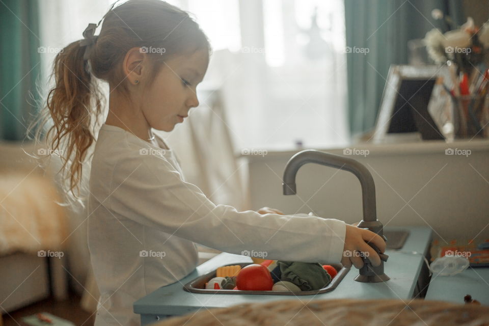 Little girl playing with Ikea kitchen in playroom 