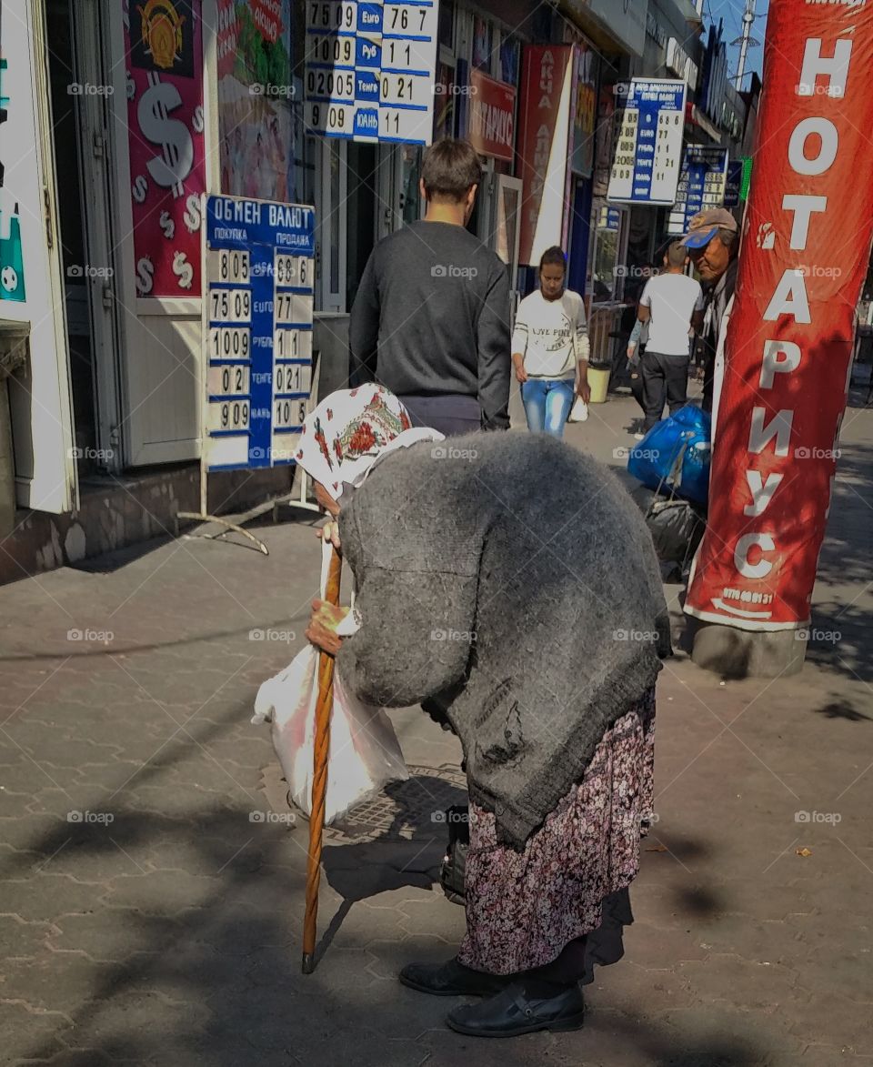 This old lady is bagging for some money. She is old and poor.