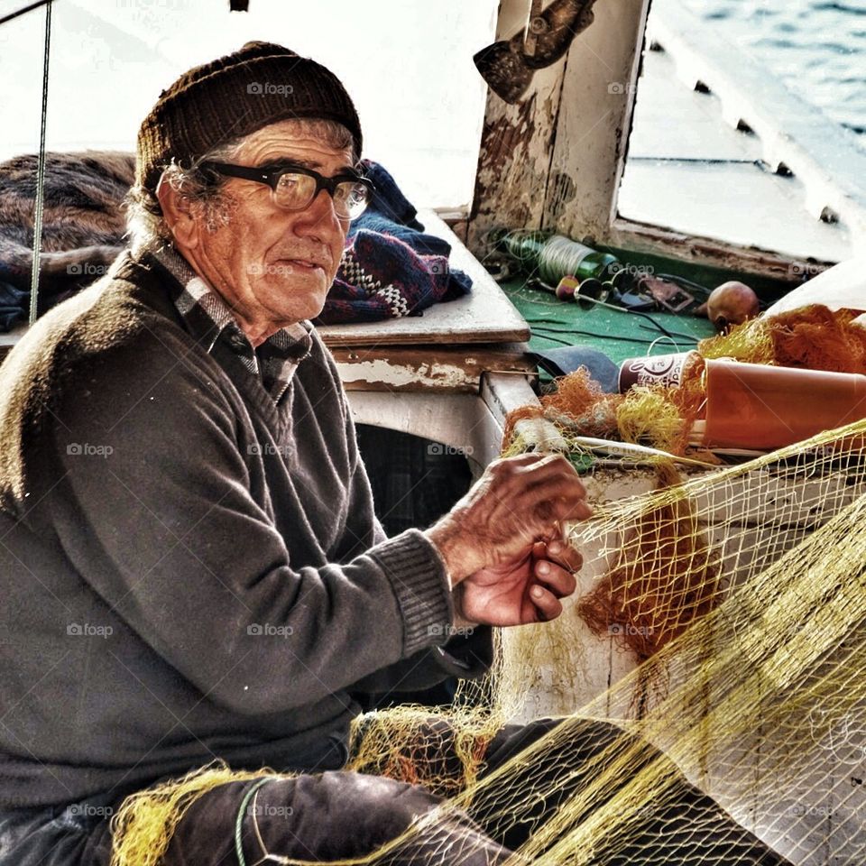 Old man maintaining fishing his fishing nets
