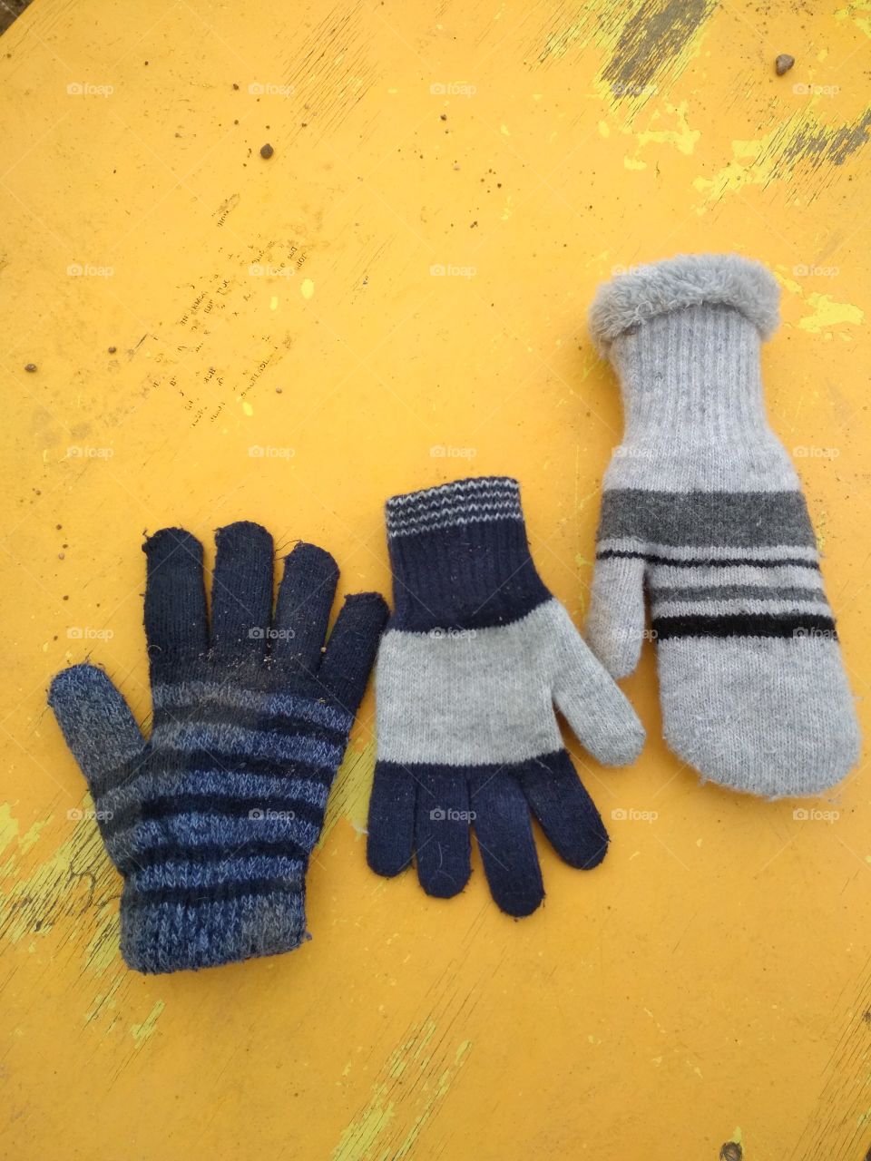 Different gloves and  mittens  on the yellow  background