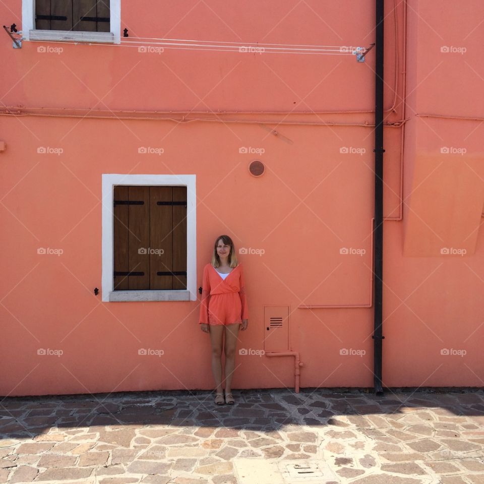 Cute girl in front of a coral pink wall 