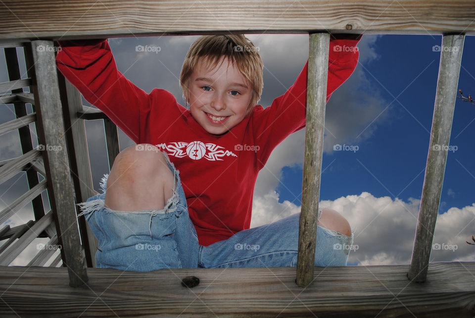 Smiling boy sitting on wood