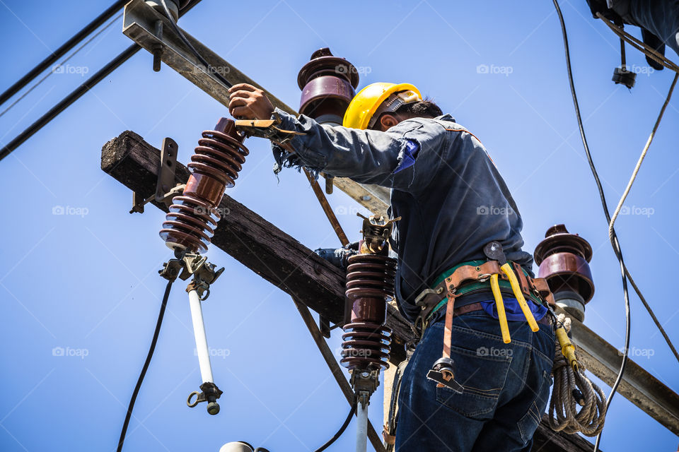 Electrician working on the electricity pole to replace the electrical insulator