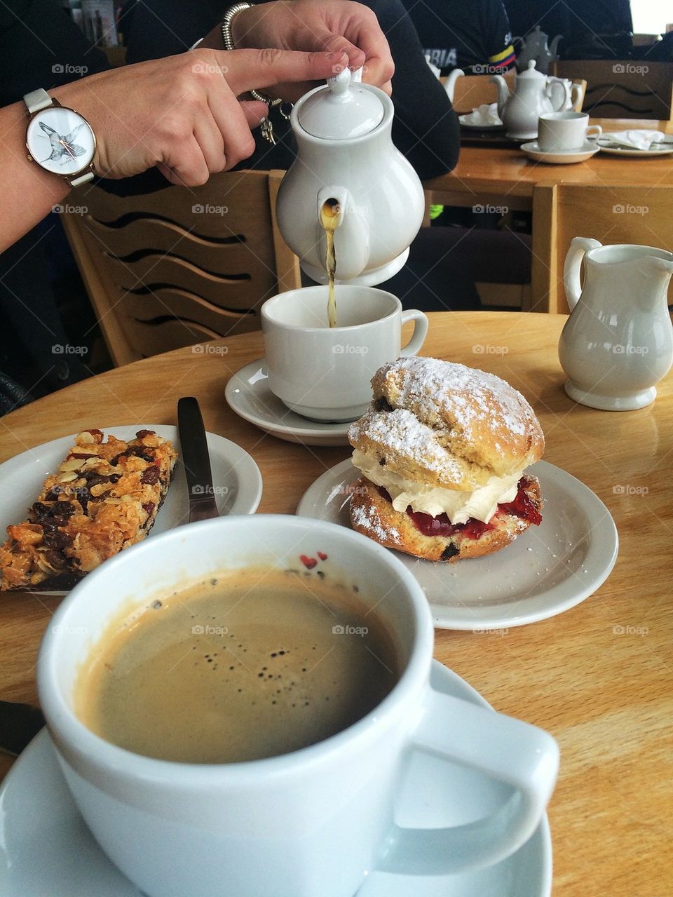 Person pouring tea and healthy breakfast on table