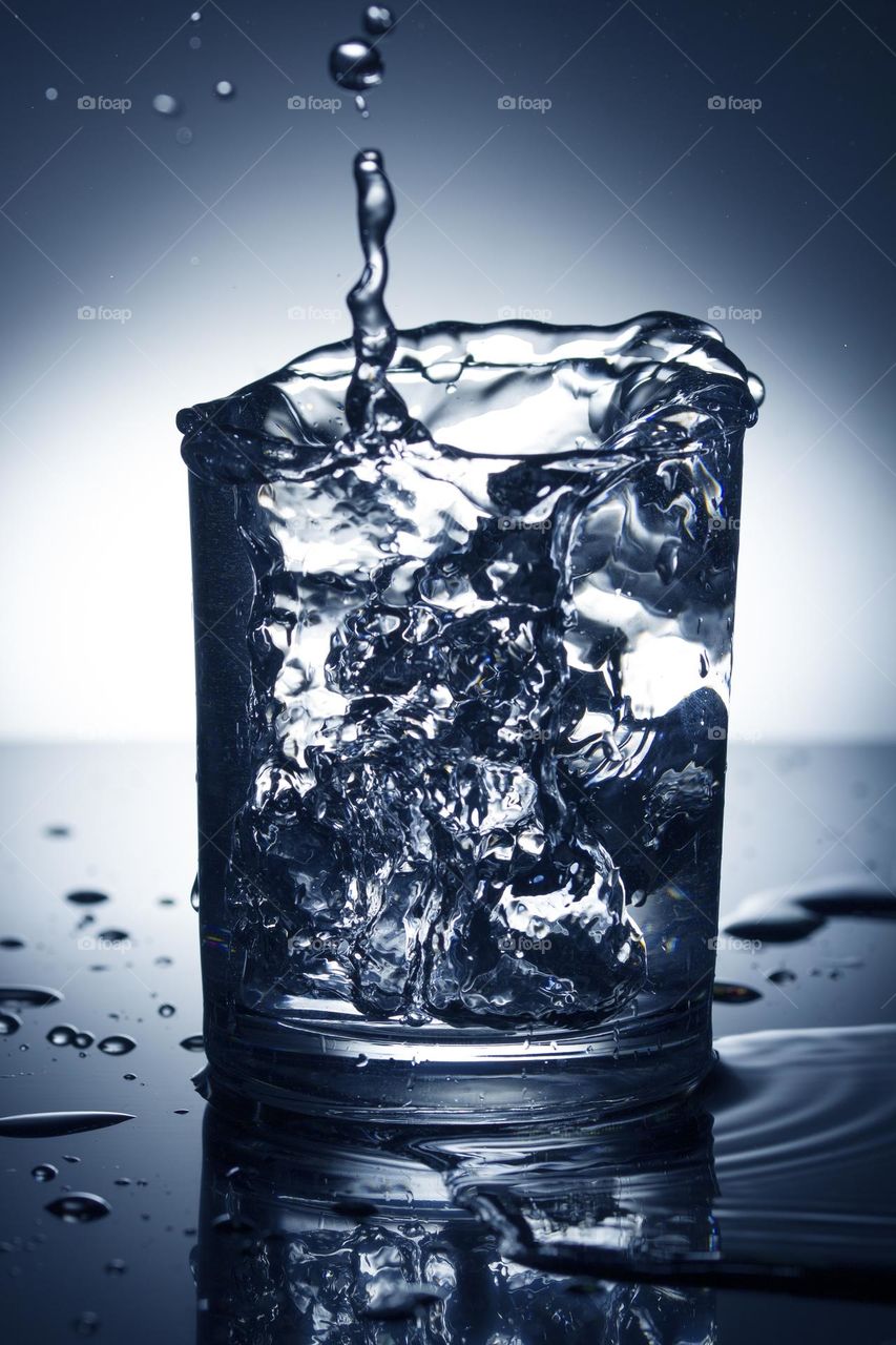 glass of water with splash from falling ice cube. Motion blur .