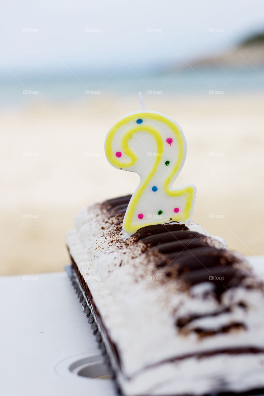 ice cream cake on beach. ice cream cake with candle number two on beach