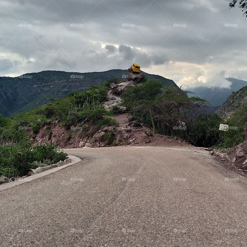 Al fondo, un vehículo en la sima de la montaña. A forma de escultura.