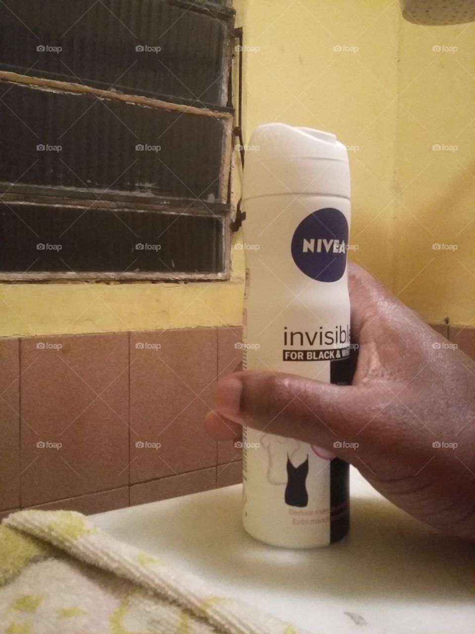 Pegando um desodorante Nivea, no banheiro.