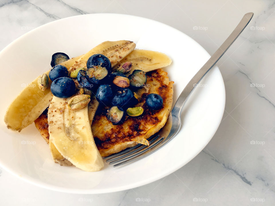 Healthy breakfast with fresh blueberries and banana french toast sprinkled with pistachios 