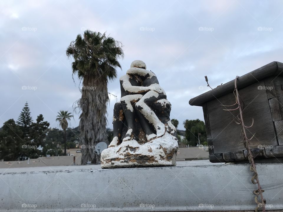 Statue of couple in love embracing in front of a palm tree. 