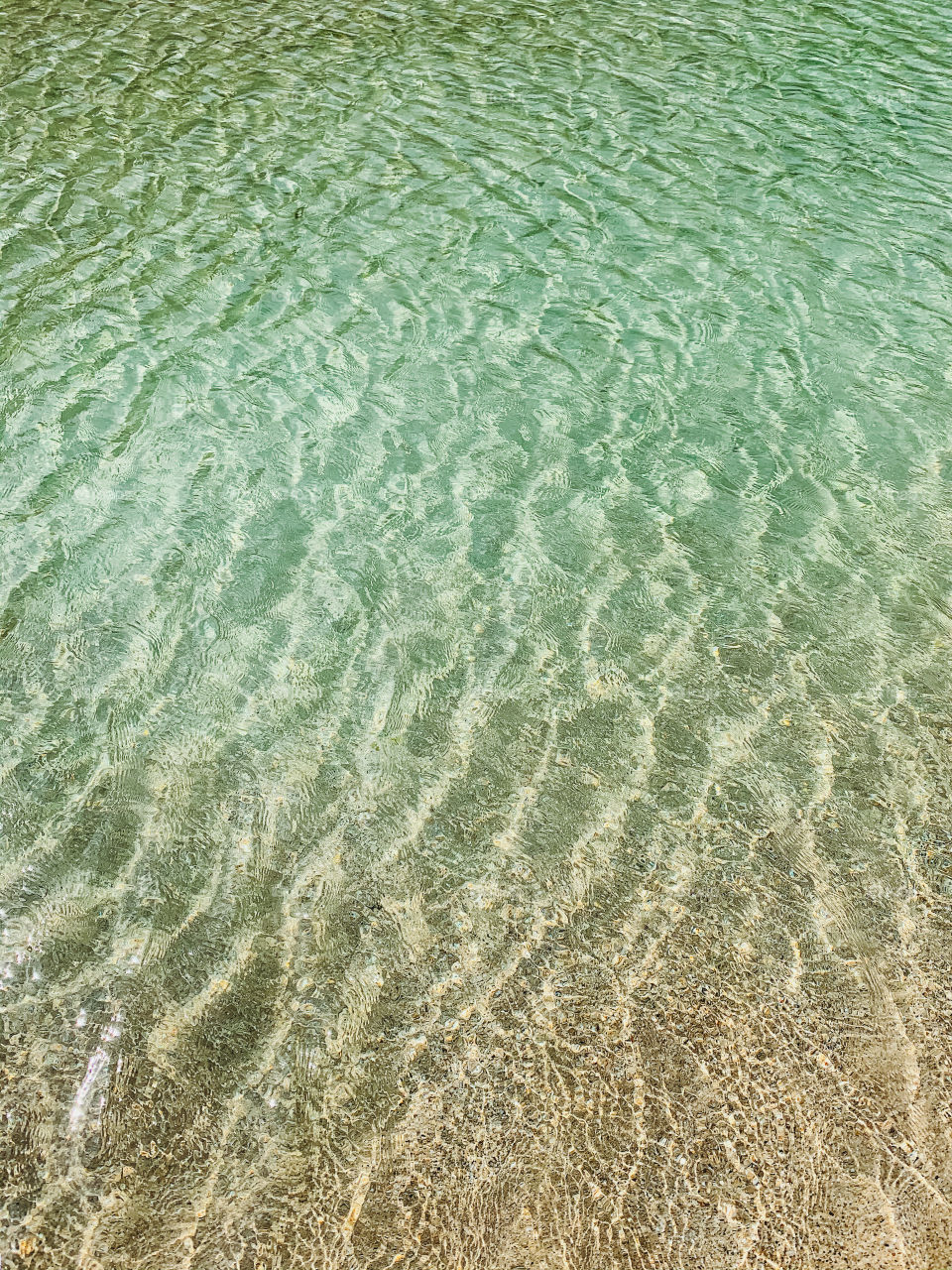 Sandy ocean bottom below turquoise blue Hawaiian waters of the Pacific Ocean. Shot from the north shore of Kauai.