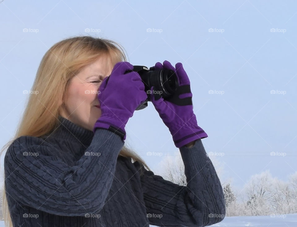 Lady taking a photograph while wearing Manzella purple gloves