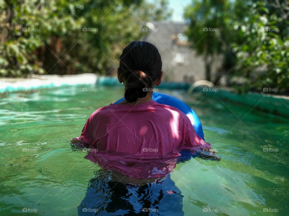 A girl in a pool with a pink shirt