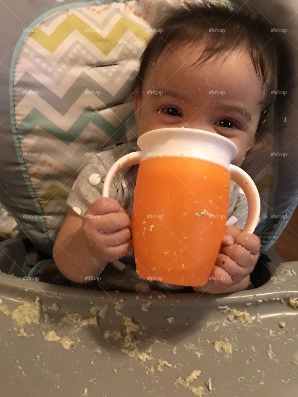 Messy baby girl drinking out of a sippy