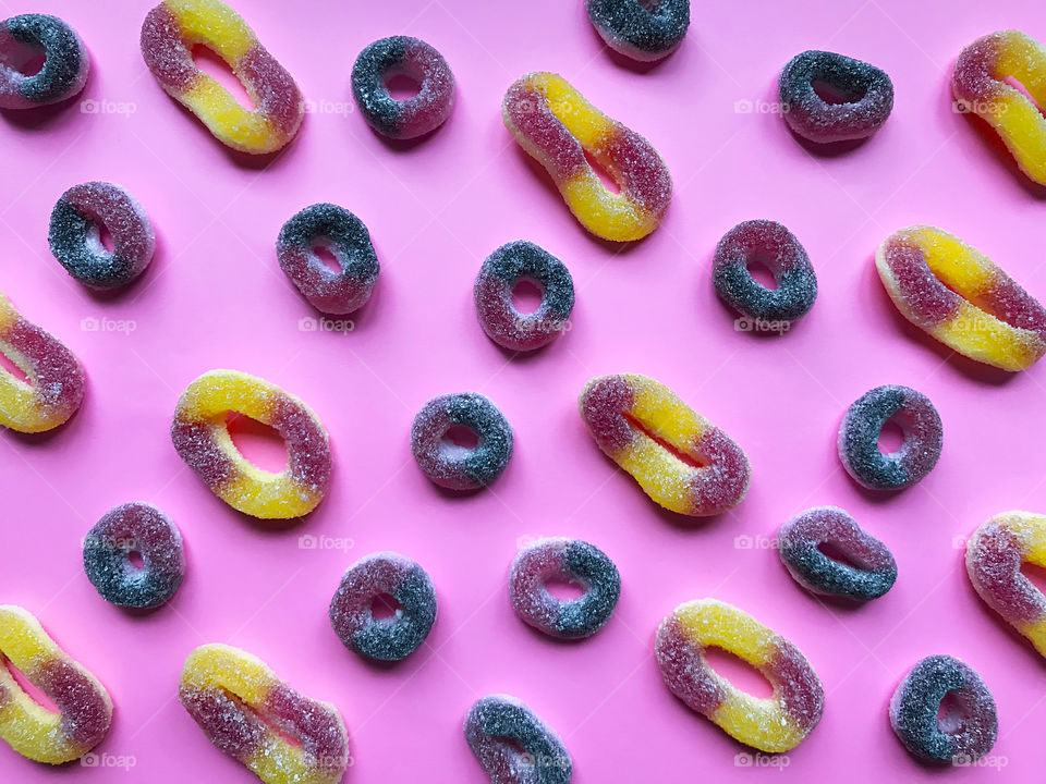 Colorful flat lay pattern made of round rubber candies on pink pastel background 