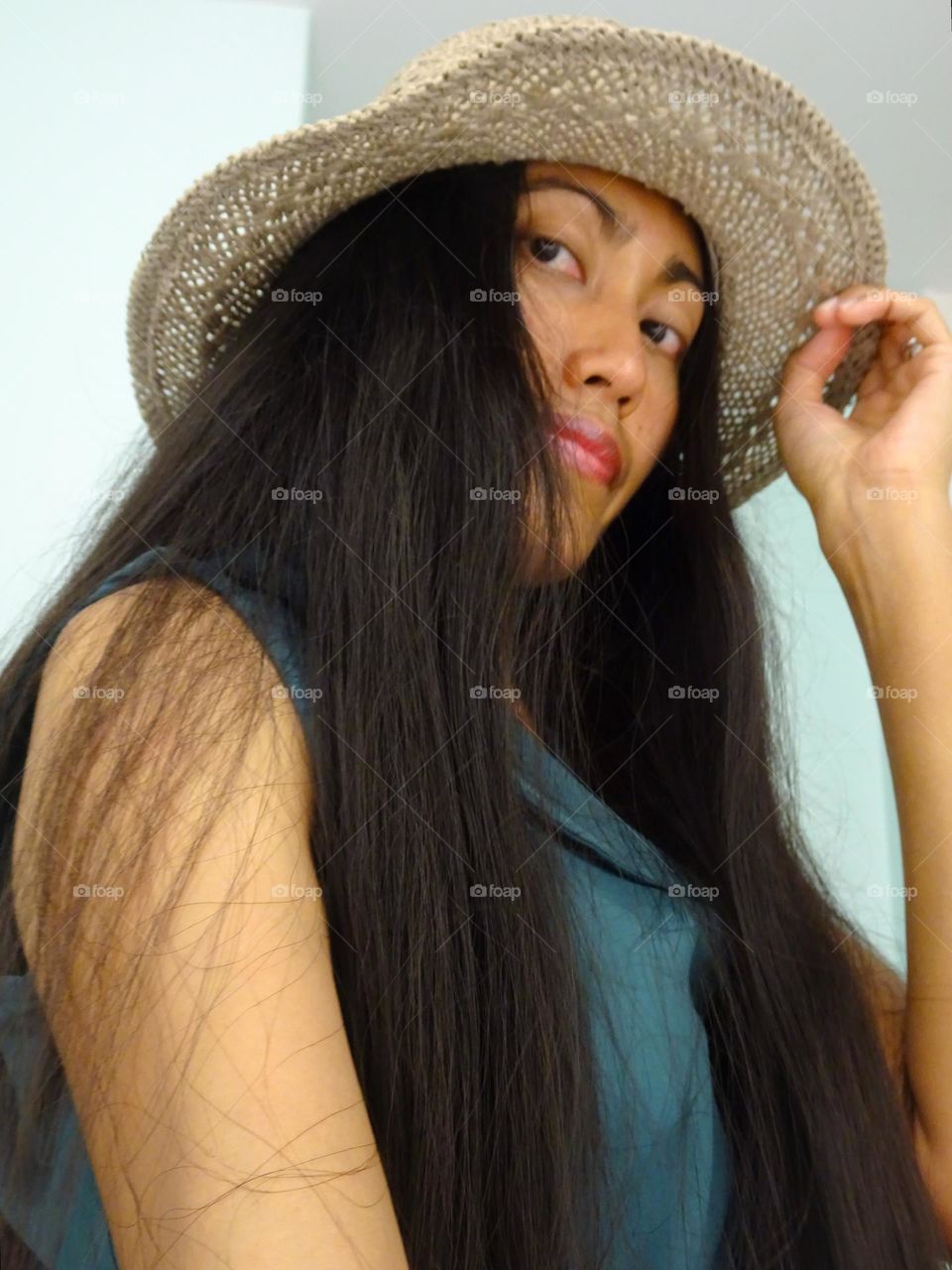 A woman with black long hair wearing a hat