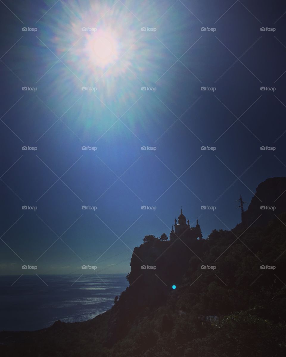 Castle standing on the edge of rock above the sea under the bright sun 