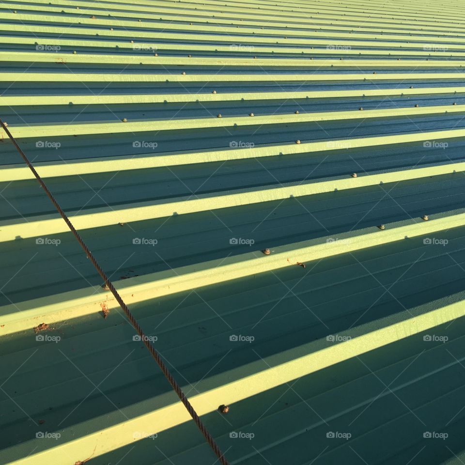 Texture and lines on this metal roof top, the sun is shining on this cool morning and the lid on this building is brightening up. 