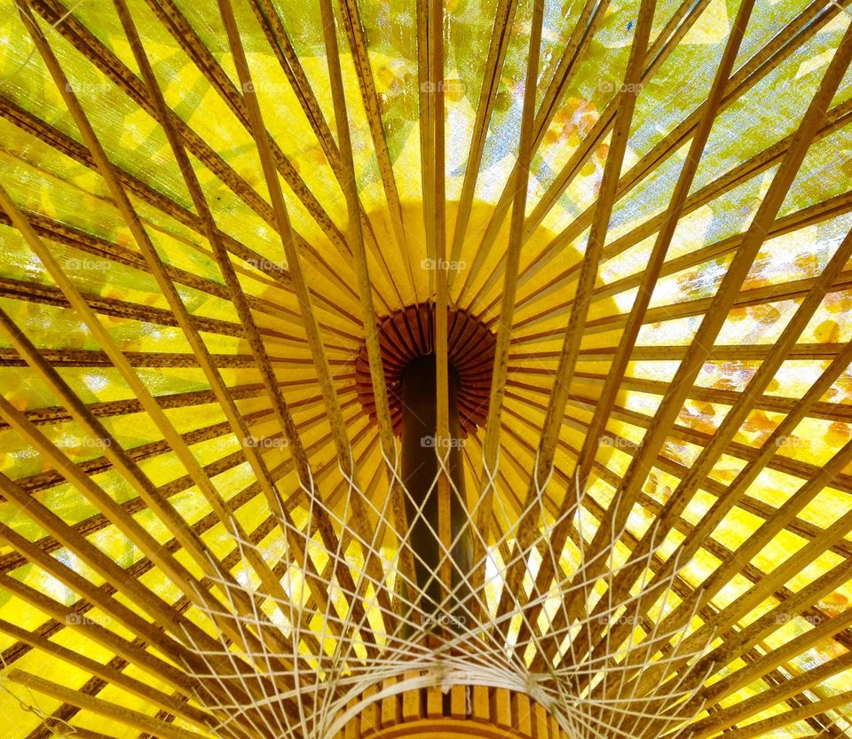 The supports of a yellow parasol form intricate patterns