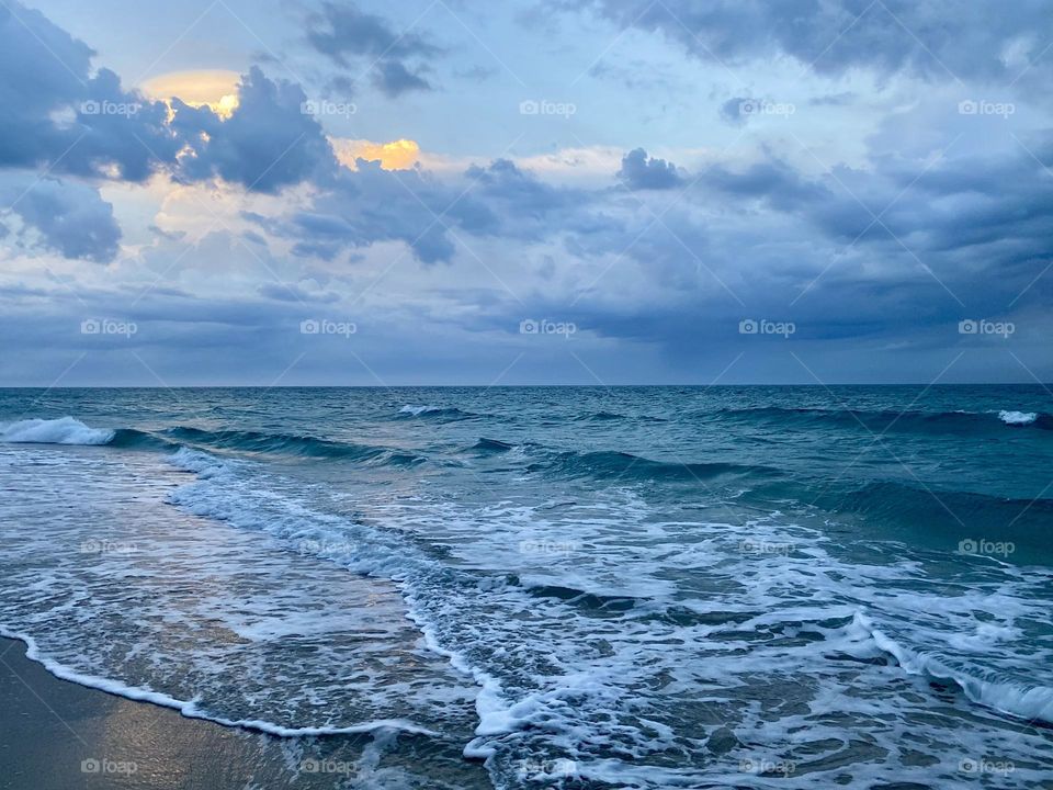 Storm clouds moving in over a beach at sunset