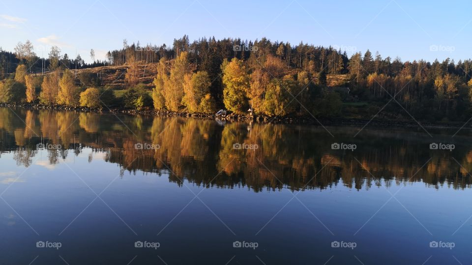 A beautiful reflection of beautiful trees dressed in autumn colors in the water of the river Götaälv Sweden