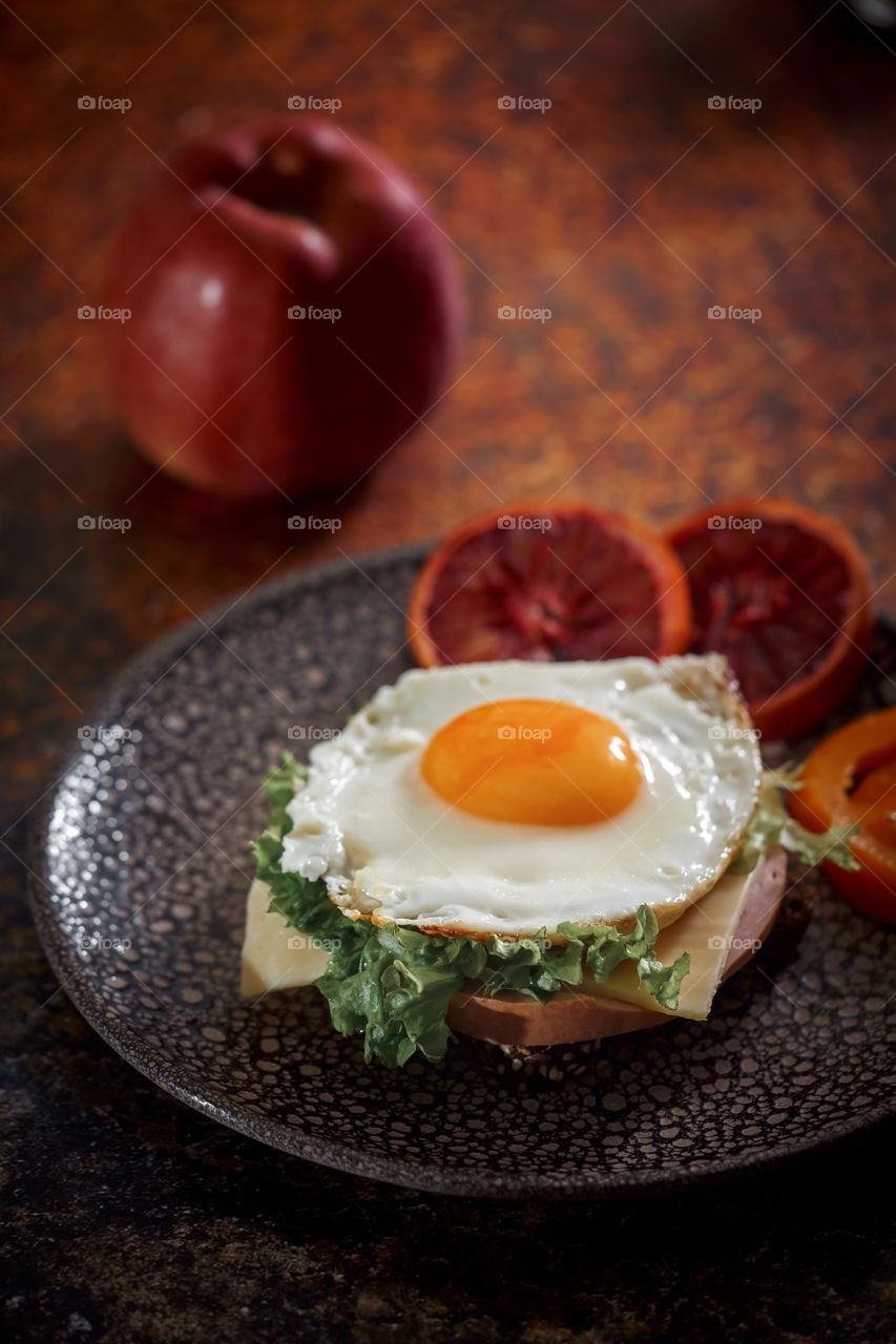 Sandwiches with fried egg orange tomato and red orange fruit 