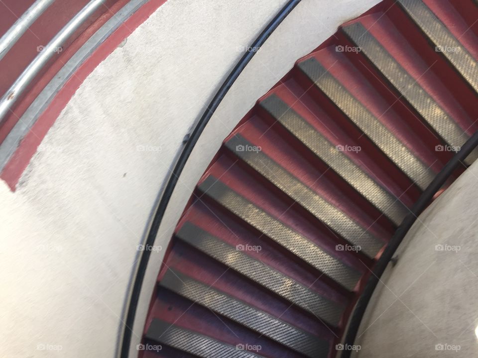 Curved red stairs leading to the top of Coit Tower in San Francisco. A hint of light highlights each step
