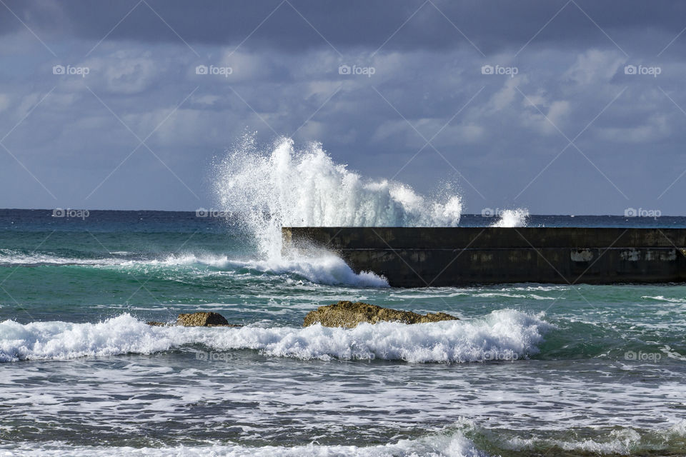 Waves crash over the harbour wall. 