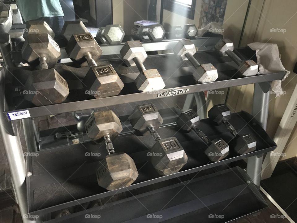 A rack of dumbbells in a gym in front of a mirror 