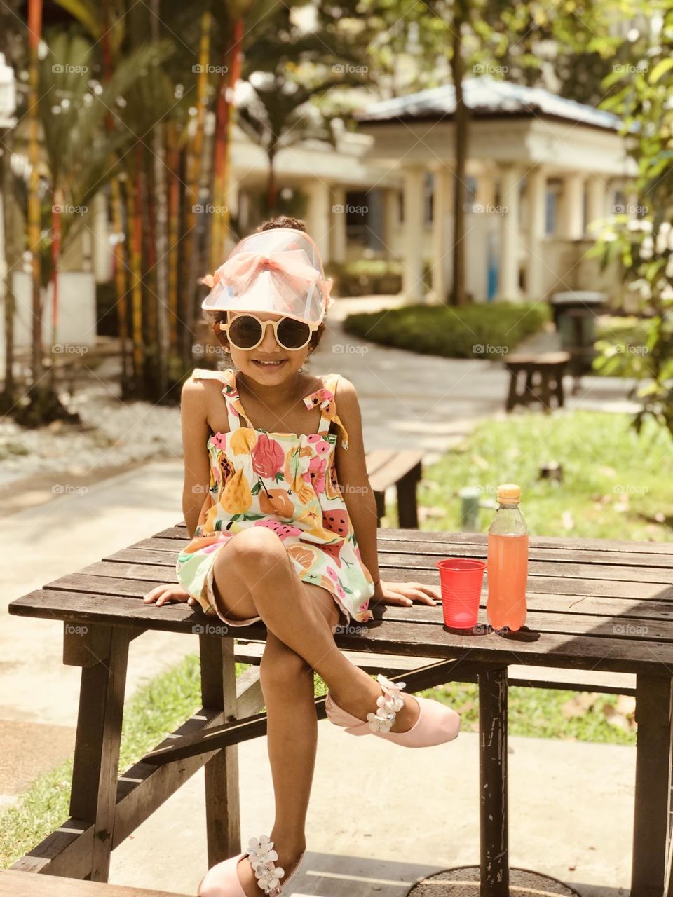 Cute little model has crazy style and sitting on wooden table and smiling 