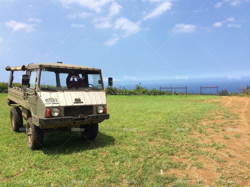 An outdoor vehicle on a hill overlooking the ocean in Hawaii.