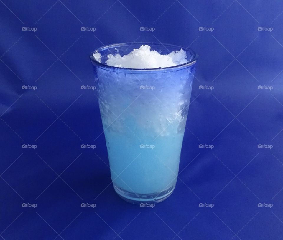 Frozen beverage in a frosty glass on a blue background 
