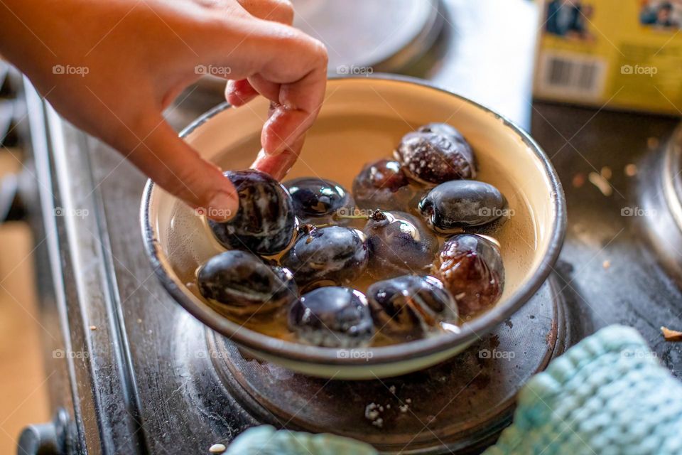 Plums in a metal bowl with water