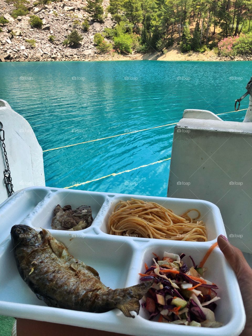 delicious lunch with fish and spaghetti in a boat cabin on the shore of a mountain lake in Turkey