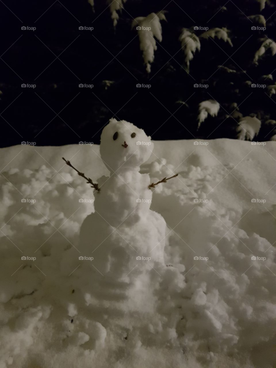 Little snowman on a table during a snowy night.