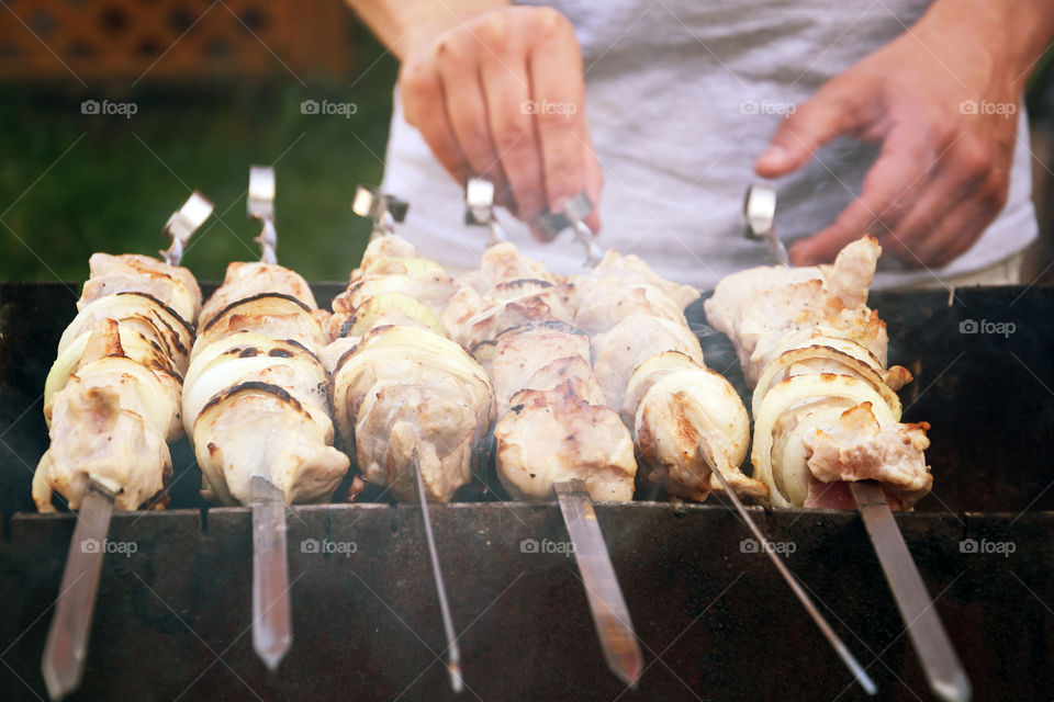 A person preparing shish kebab